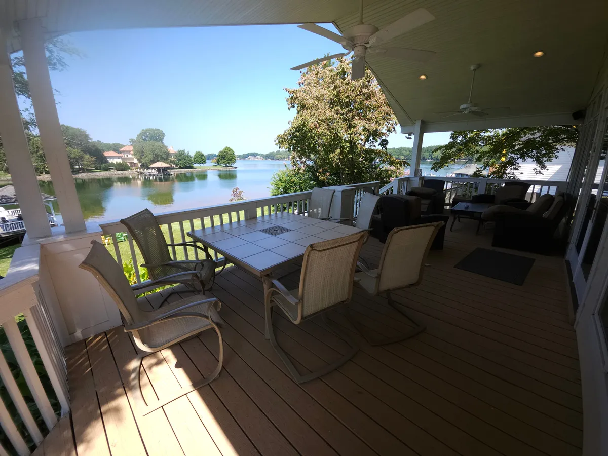 An outdoor dining table with comfortable seating overlooks the lake, surrounded by lush greenery. The space exudes tranquility and is designed for dining, relaxing, and soaking in the beautiful lakeside views during any time of day, especially at sunset.