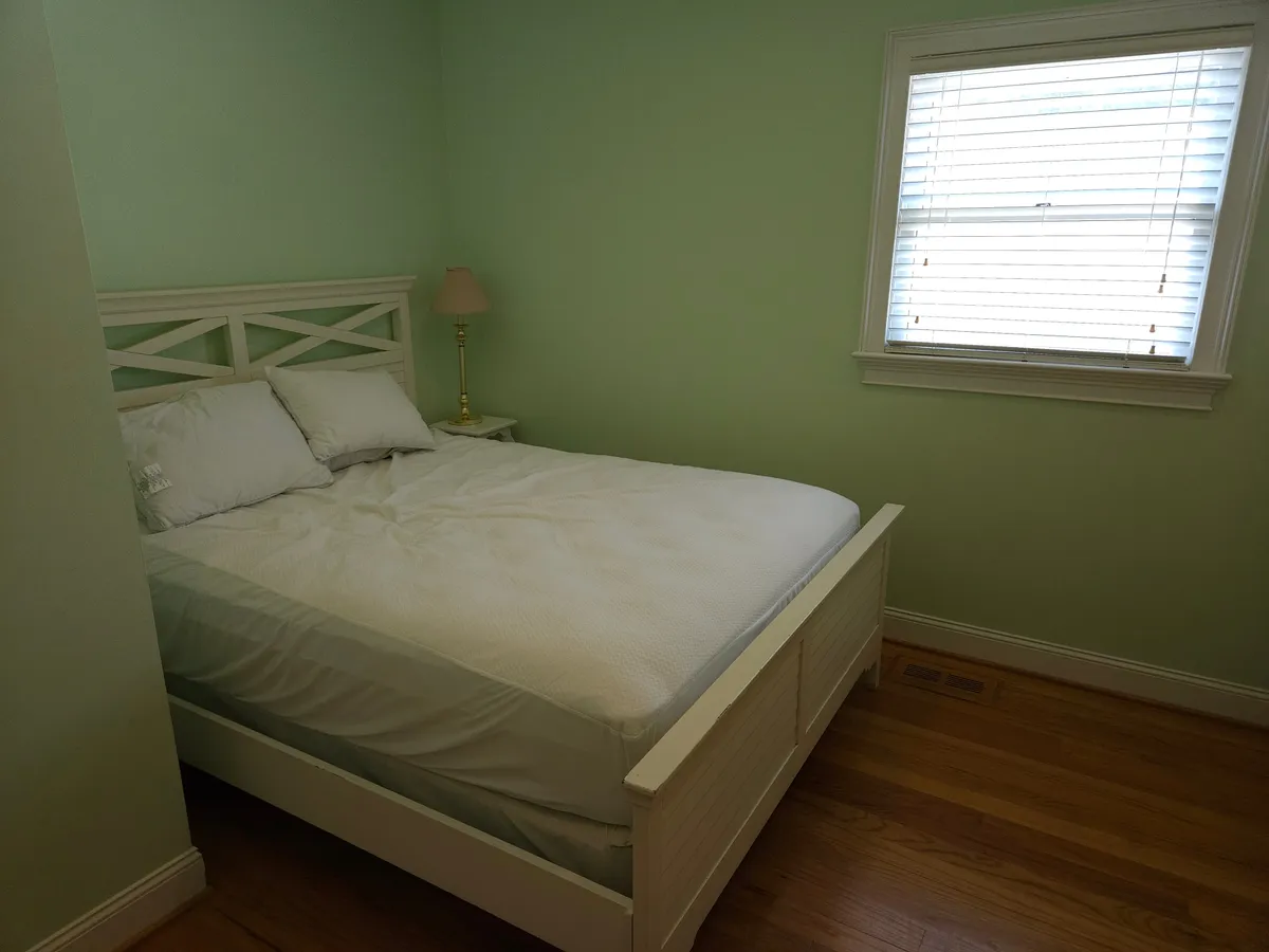 A tranquil bedroom with a comfortable bed, bedside lamp, and a window that lets in natural light. The scene suggests a quiet space for reading or unwinding after a day on the lake.